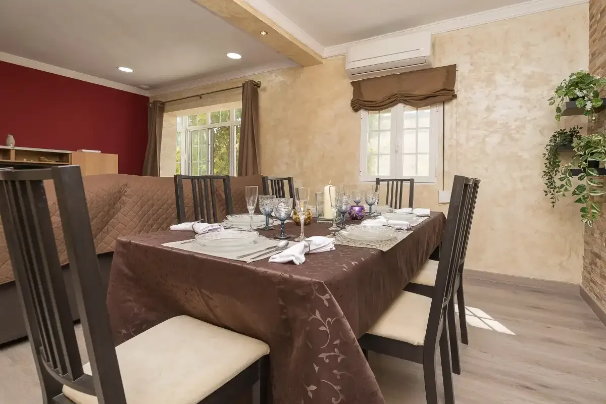 Dining area with a table set for a meal beside two windows.