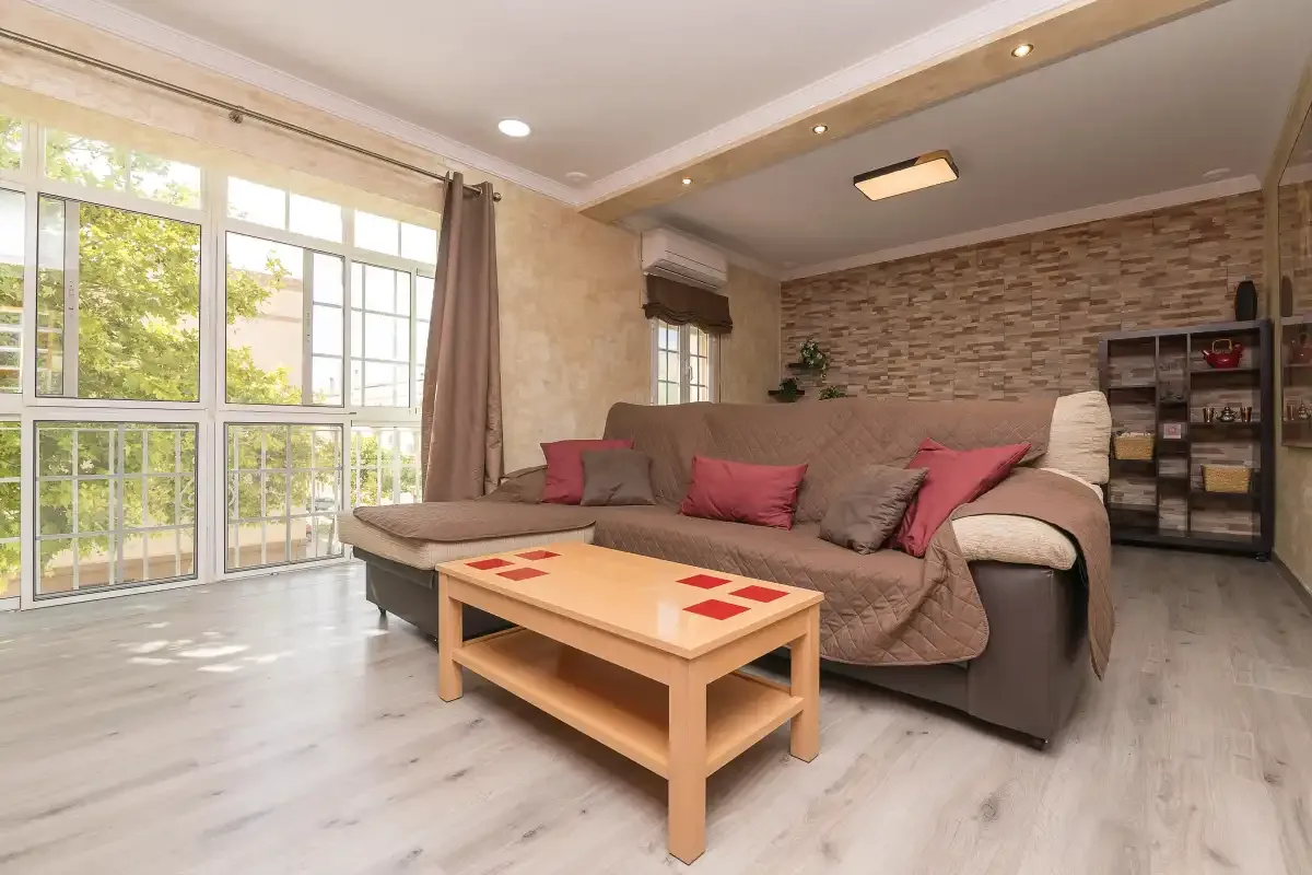 A living room with seating, a coffee table, and large windows.