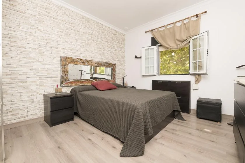 A bedroom with a neatly made bed beneath an open window.
