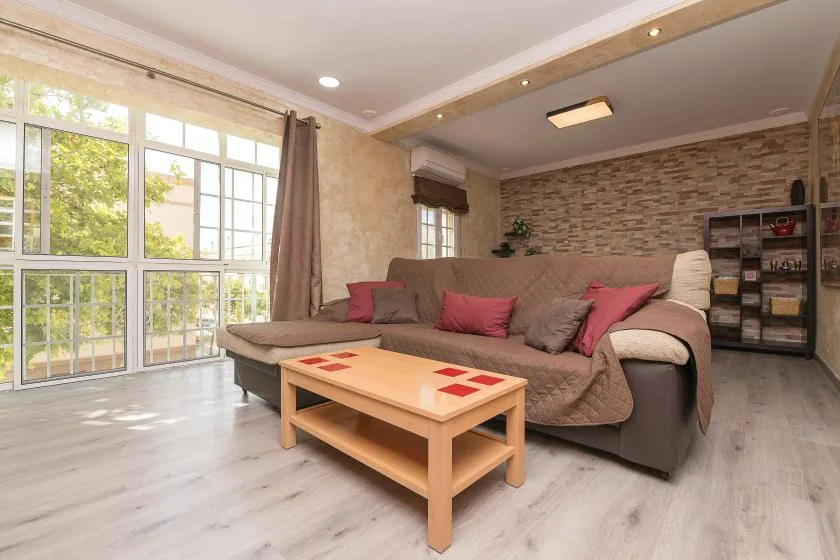 A living room with a sectional seating area and a wooden coffee table.