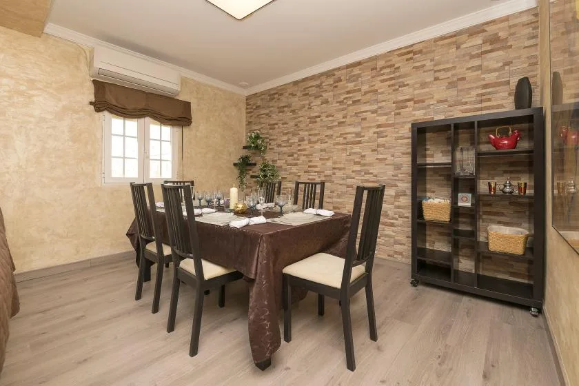 A dining area with a table set beside a window and display cabinet.