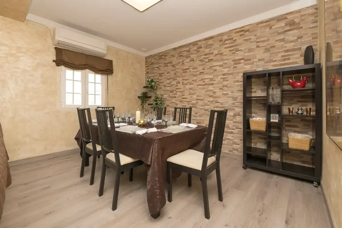 A dining room with a set table and dark shelving against a brick-patterned wall.