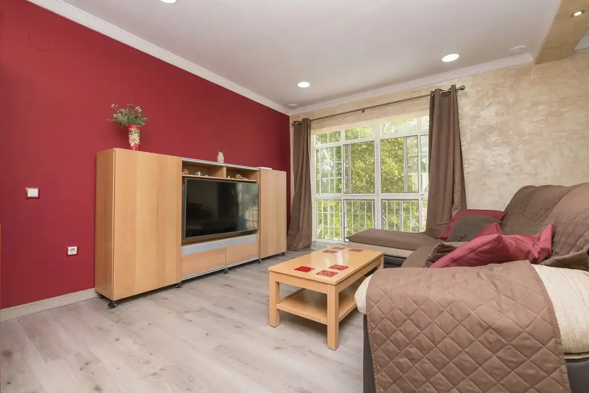 A living room with a television cabinet, coffee table, and seating by the window.