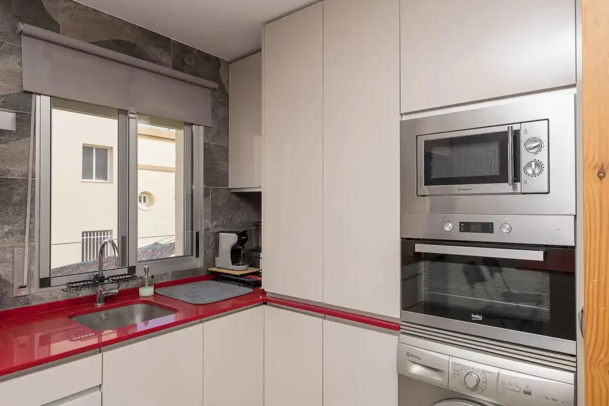 A modern kitchen with red countertops and built-in appliances.