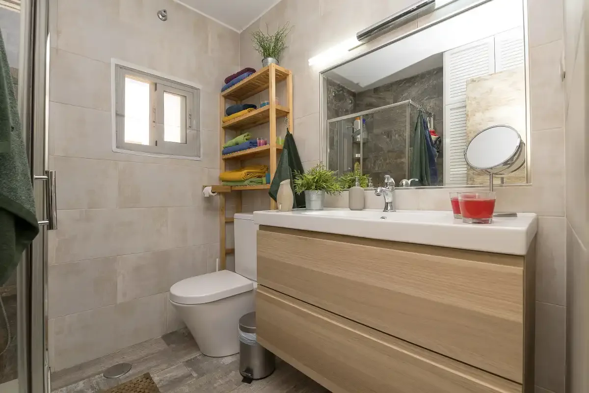 A tiled bathroom with a vanity, mirror, and shower.