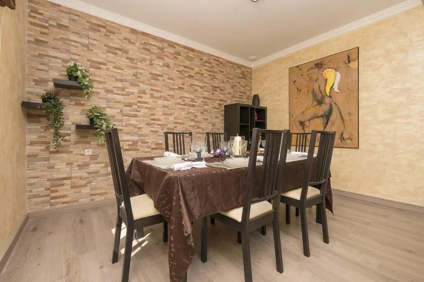 Comedor con una mesa preparada para comer y asientos oscuros.