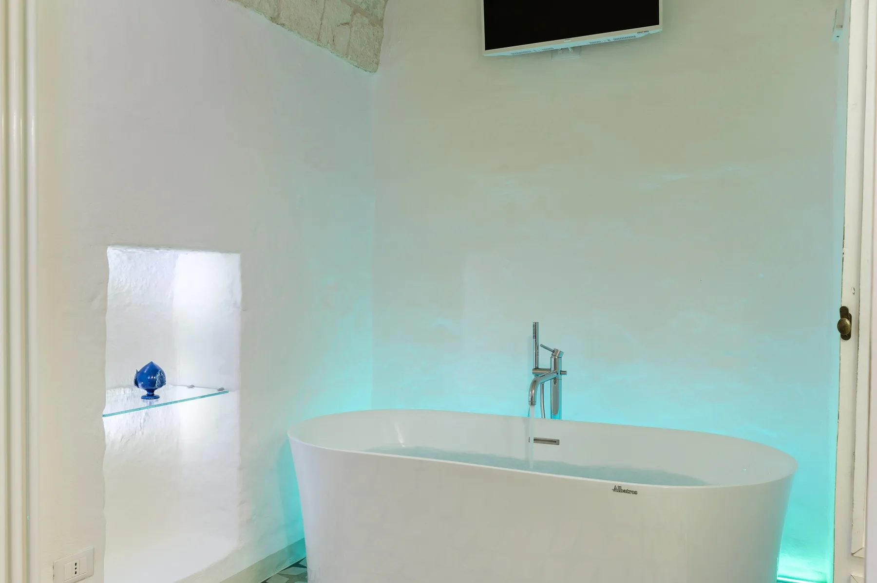 A bathroom with a freestanding bathtub and wall-mounted television.