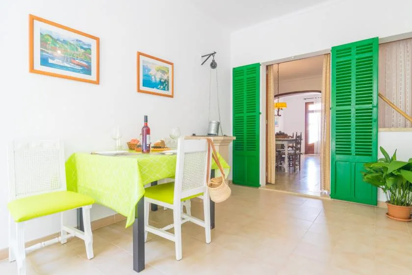 A bright dining area with a lime-green tablecloth and open green shutters.