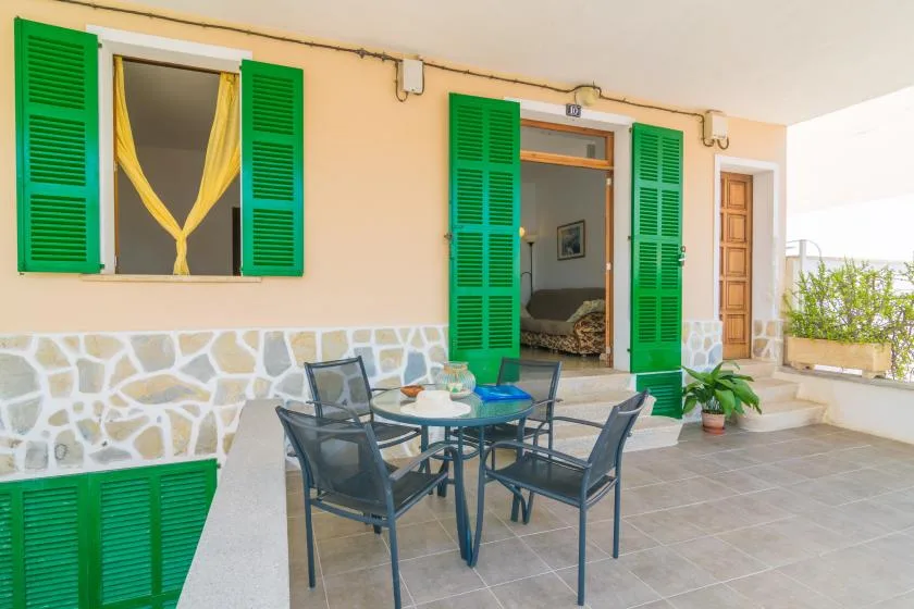A tiled patio with an outdoor table and chairs beside an open doorway.