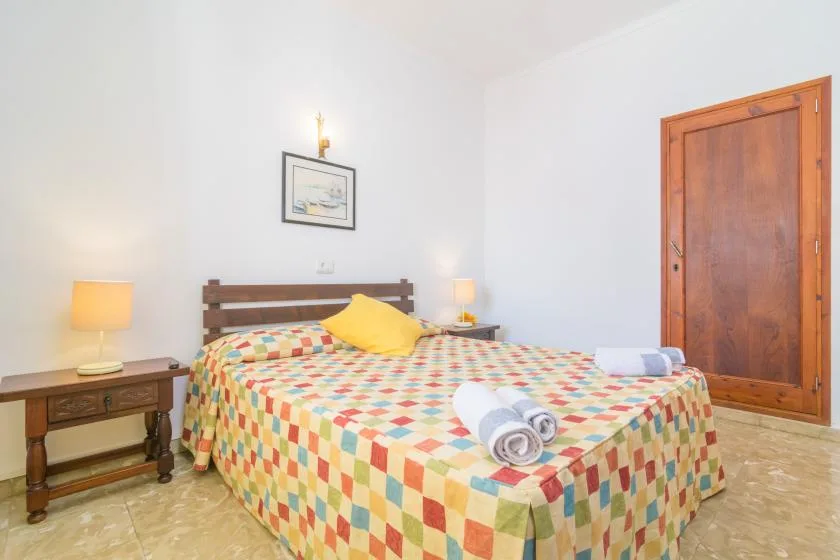 A bedroom with a wooden bed, colorful patchwork bedding, and bedside tables.