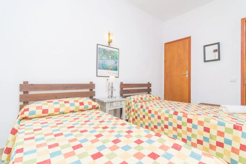 A bedroom with two beds covered in colorful patchwork quilts.