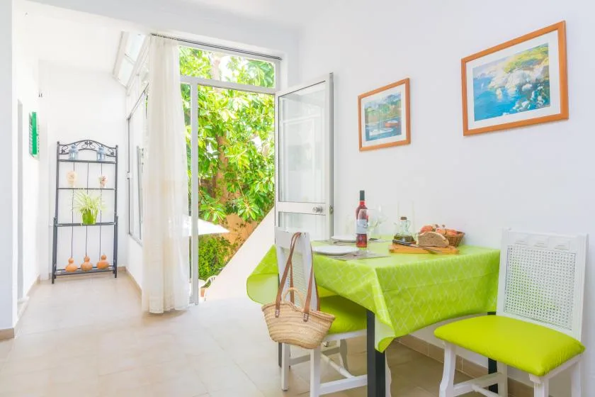 A bright dining area with a green-covered table beside an open garden doorway.