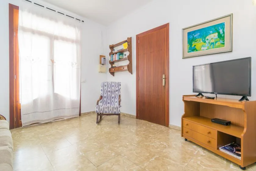 A living room with a television on a wooden stand and a patterned chair.