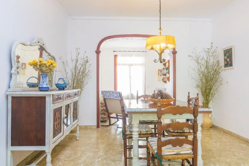 A dining room with a wooden table and chairs beneath a hanging light.