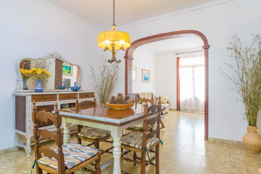 A dining room with a wooden table and chairs beneath a hanging light.