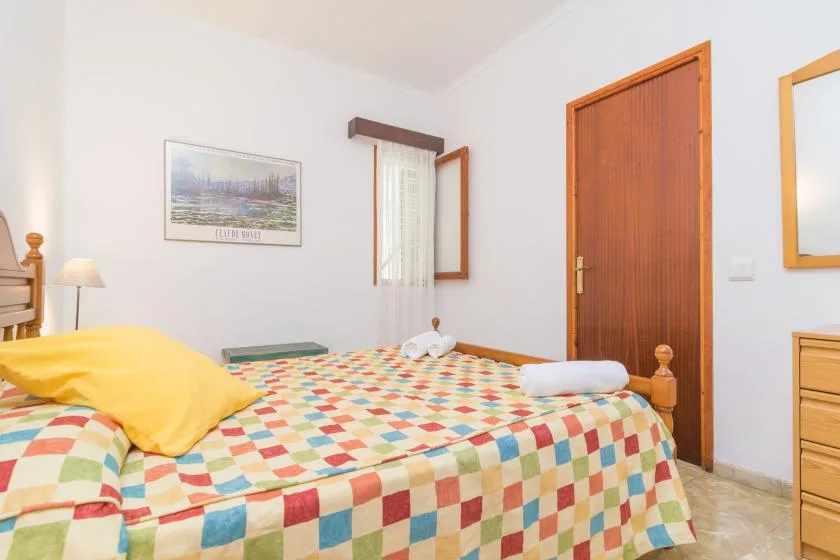 A bedroom with a bed covered by a colorful patchwork quilt.