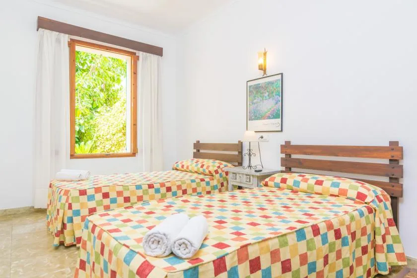 A bright bedroom with two beds covered in colorful patchwork bedding.