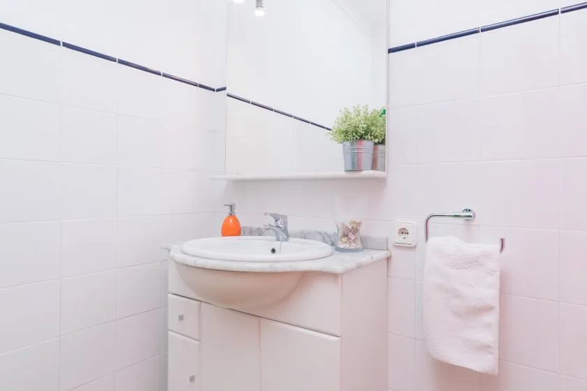 A bright bathroom with a sink, mirror, and towel.