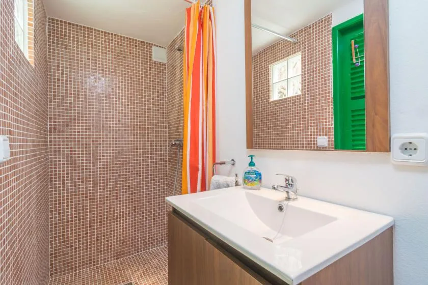 A tiled bathroom with a shower curtain and a sink beneath a large mirror.