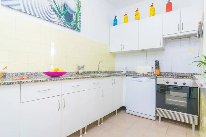 A bright kitchen with white cabinets, a countertop, and an oven.