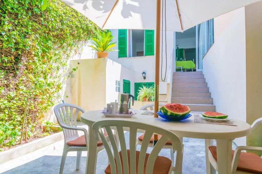 An outdoor dining area with a table and chairs beneath a large umbrella.