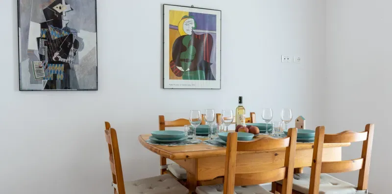 Un comedor con una mesa de madera puesta con platos y cristalería.