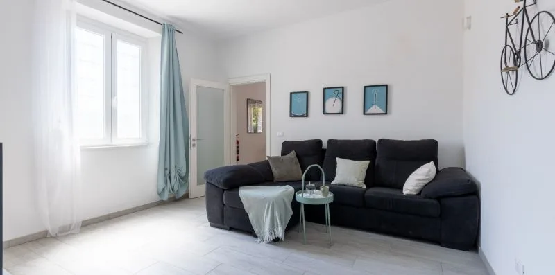 Una sala de estar con asientos oscuros, una pequeña mesa de vidrio y cuadros en la pared.