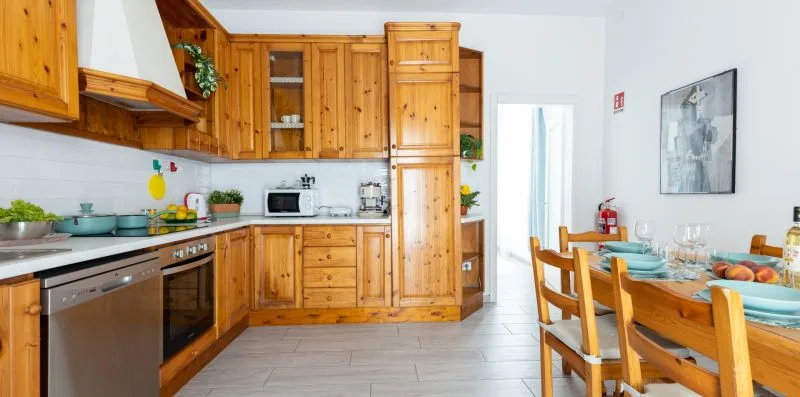 Una cocina revestida de madera se abre a un comedor con la mesa puesta.