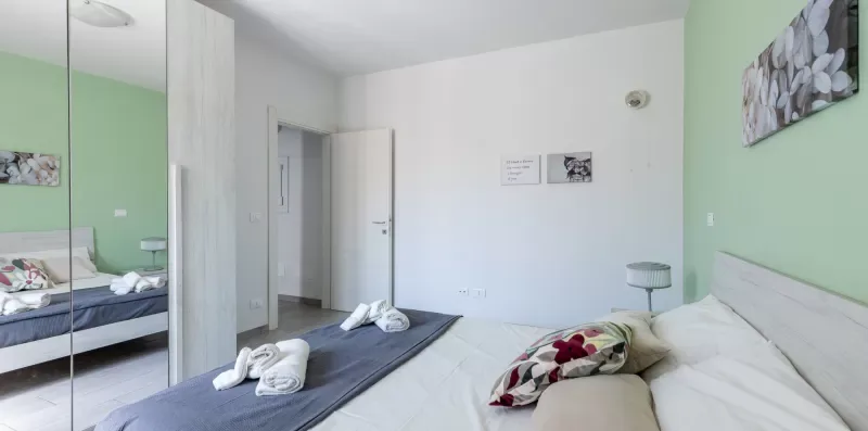 Un dormitorio con camas, toallas dobladas y paredes verde claro.