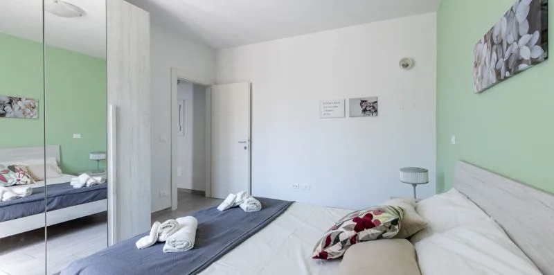 Un dormitorio con ropa de cama blanca y una pared verde.