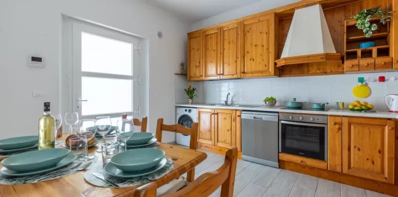 Una cocina con gabinetes de madera y una mesa de comedor puesta con vajilla.