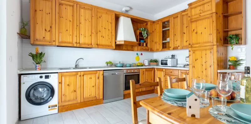 Una cocina luminosa con gabinetes de madera y una mesa puesta con platos.