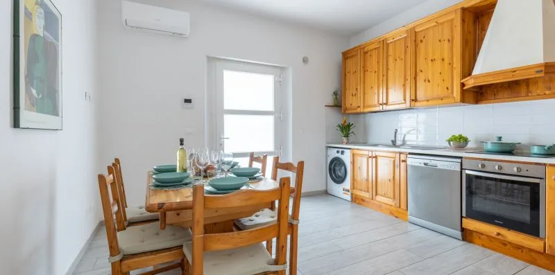 Una cocina y comedor con armarios de madera y una mesa puesta con platos.