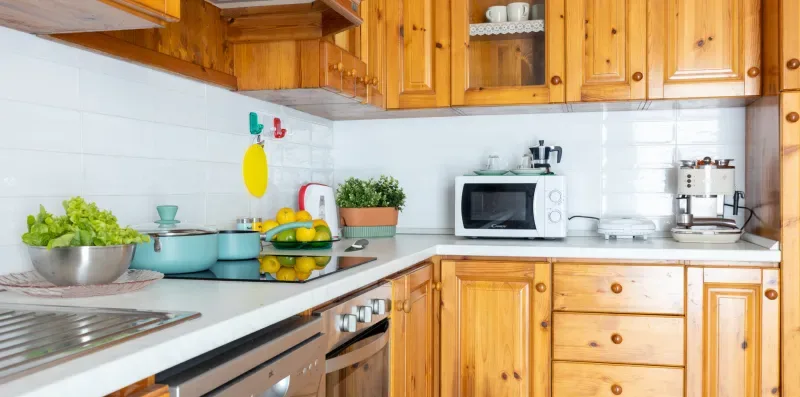 Una cocina con gabinetes de madera, encimeras blancas y electrodomésticos.