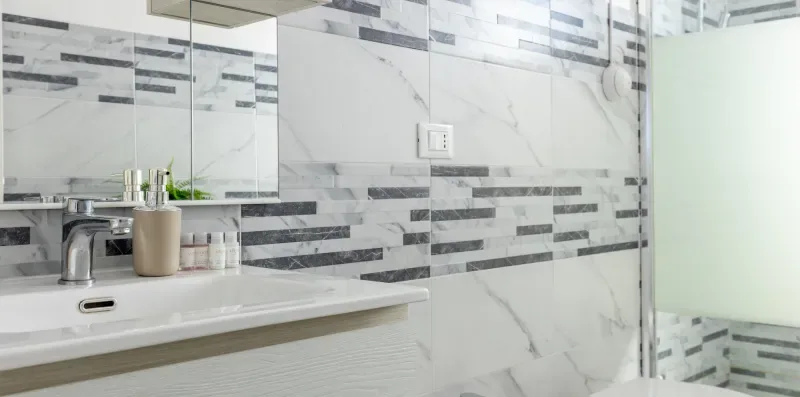 Un baño alicatado con lavabo y mampara de ducha de vidrio.