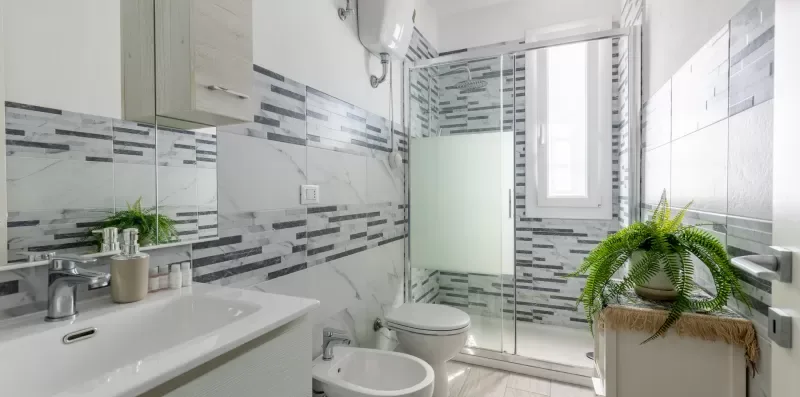 Un baño luminoso con lavabo, inodoro, bidé y ducha de vidrio.