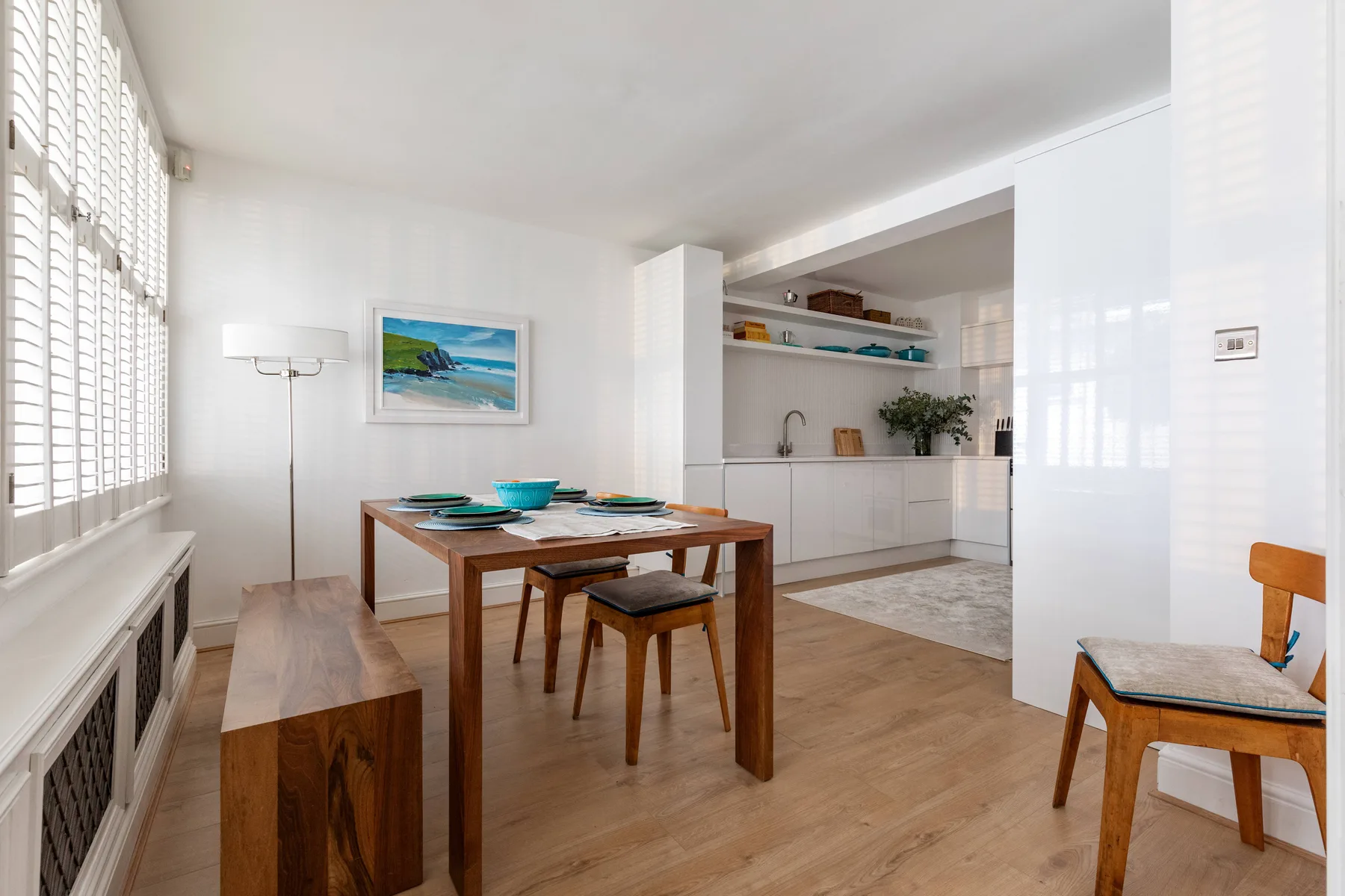 A bright dining area with a wooden table beside a kitchen.