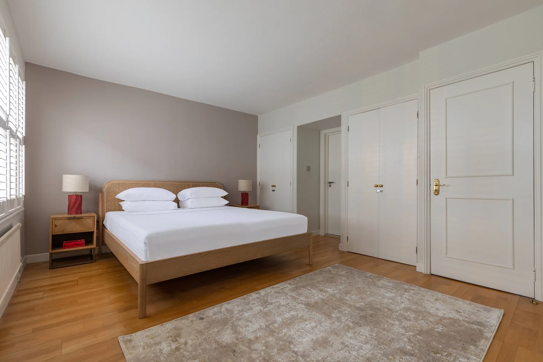 A bedroom with a bed, bedside tables, and a rug on the floor.