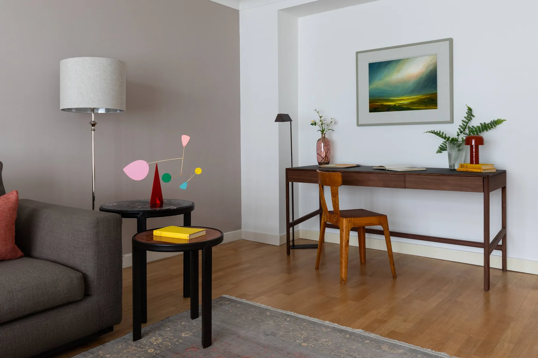 A living room with seating, a desk, and a framed landscape painting.