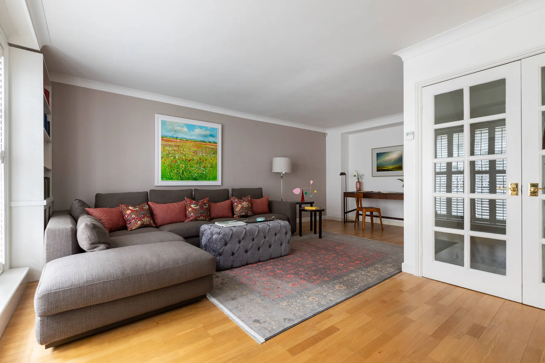 A living room with a sectional seating area, colorful artwork, and a rug.