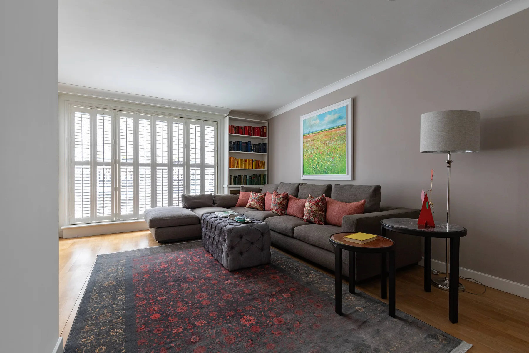 A living room with seating, a patterned rug, and large windows.
