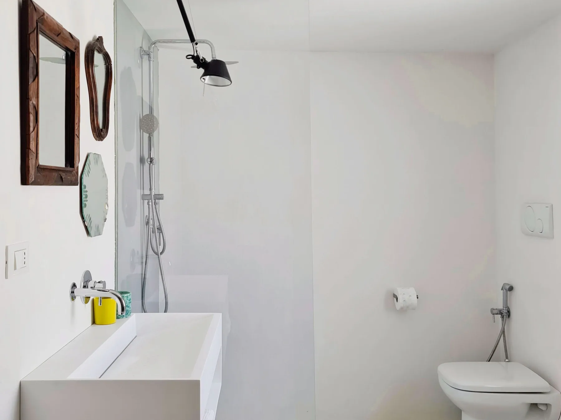 Un baño luminoso con bañera, ducha e inodoro suspendido.