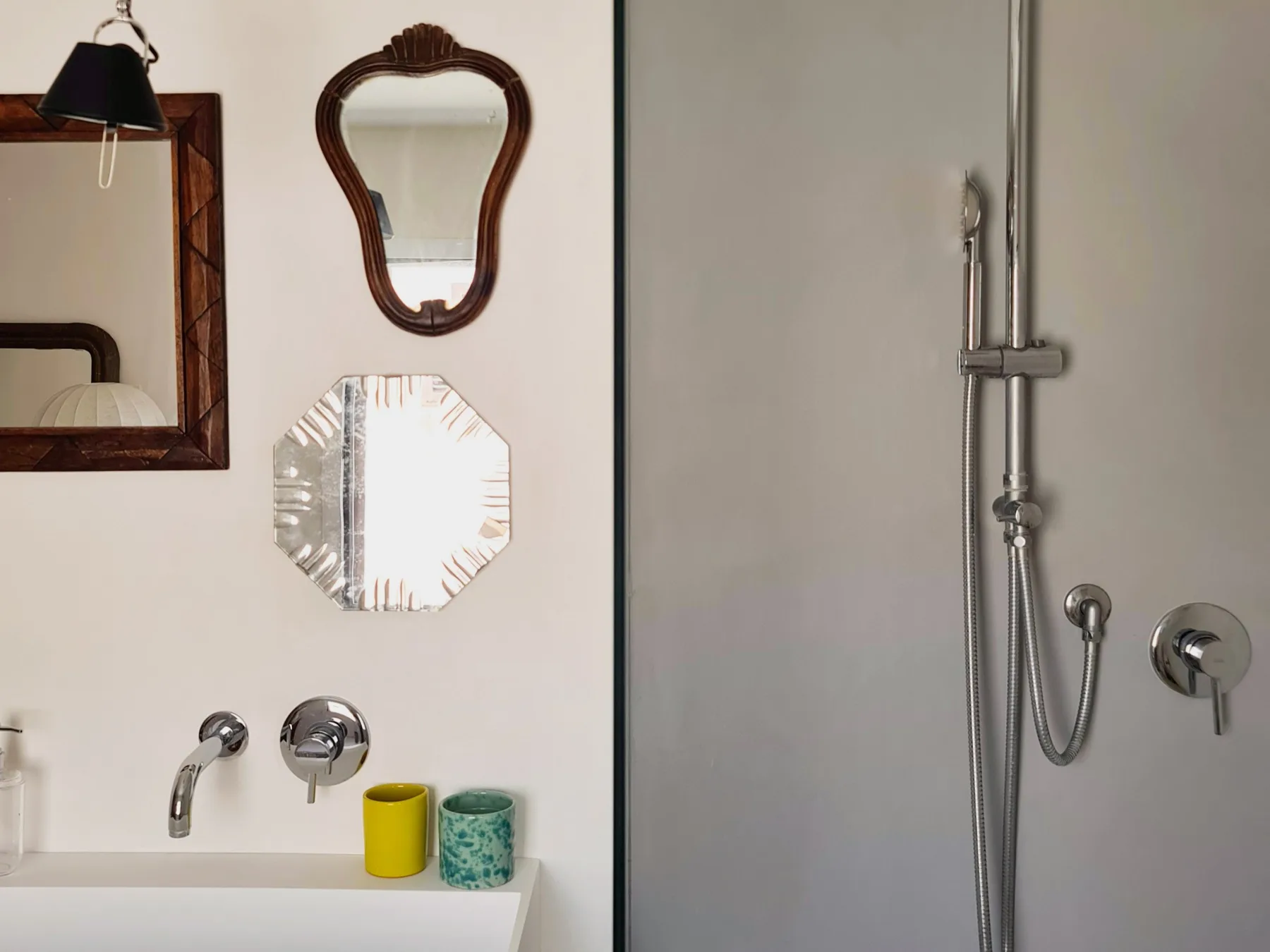 Un tocador de baño con espejos y una ducha de pared.