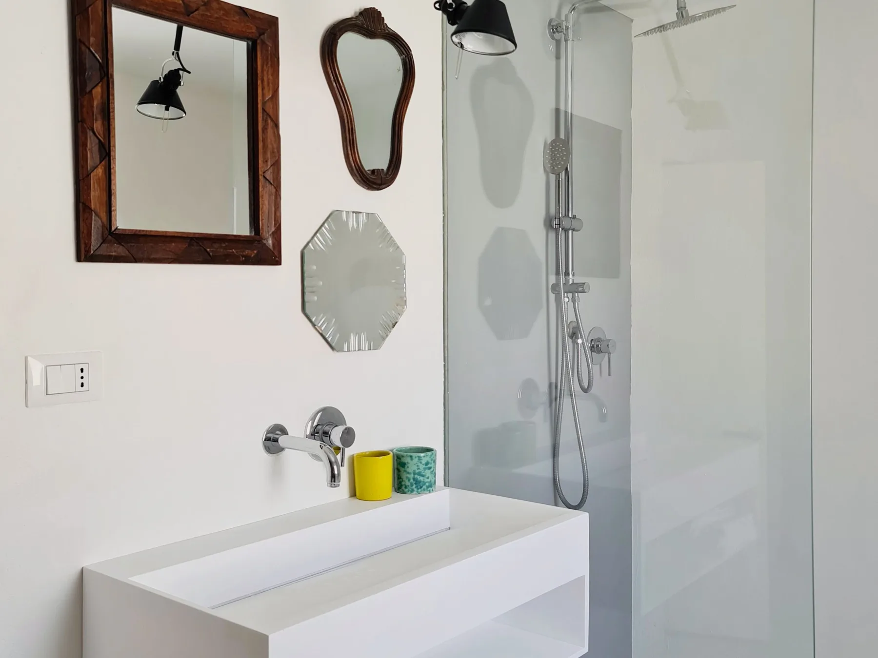 Un baño luminoso con un lavabo blanco y una ducha de vidrio.