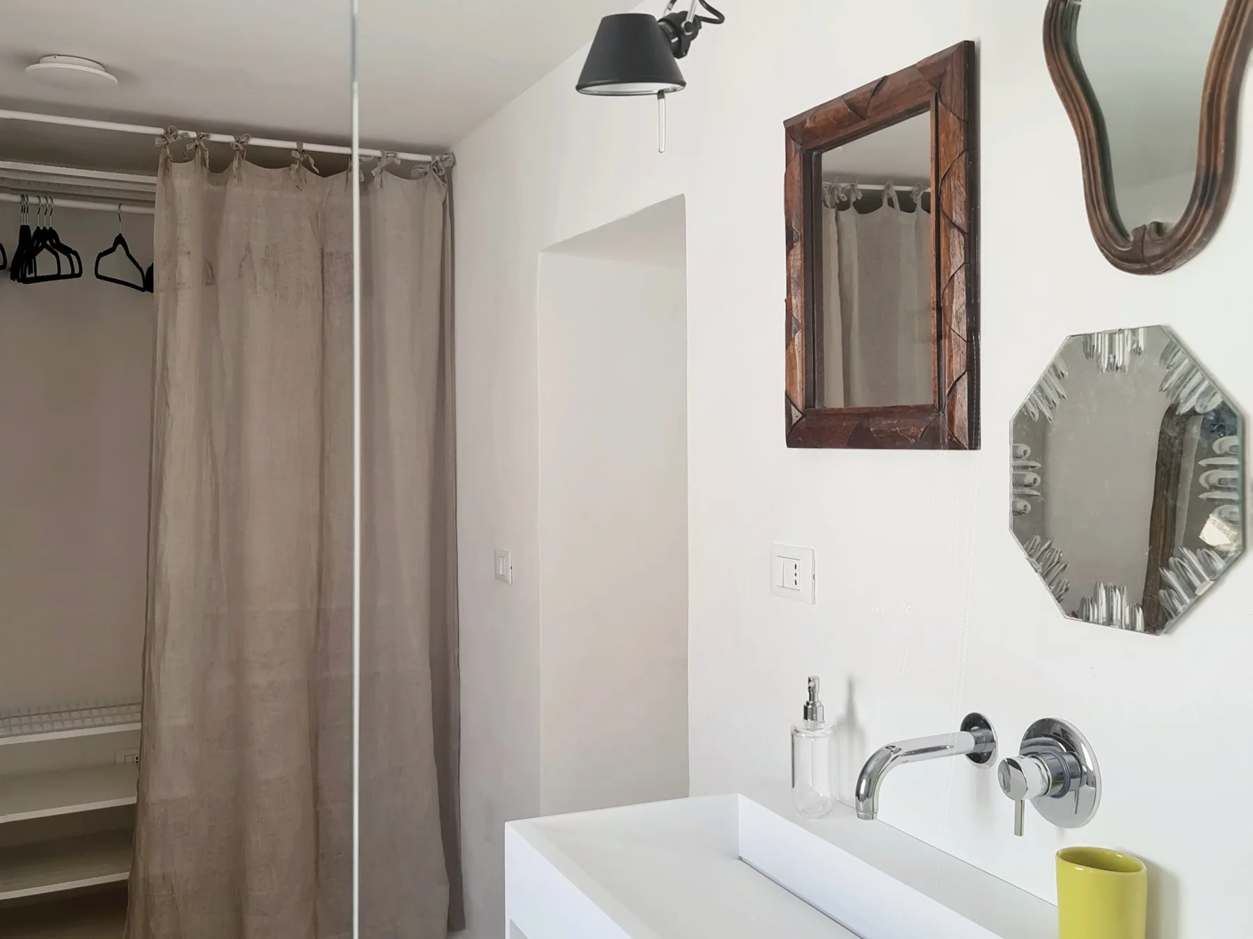 Un lavabo de baño con espejos de pared junto a una ducha con cortina.