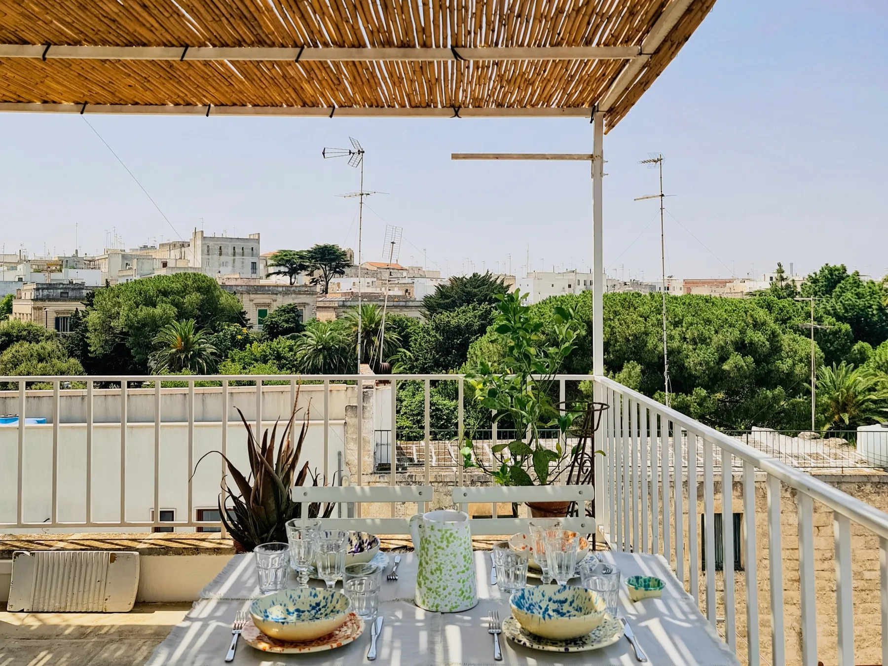 Una terraza en la azotea con una mesa de comedor bajo un toldo de listones.