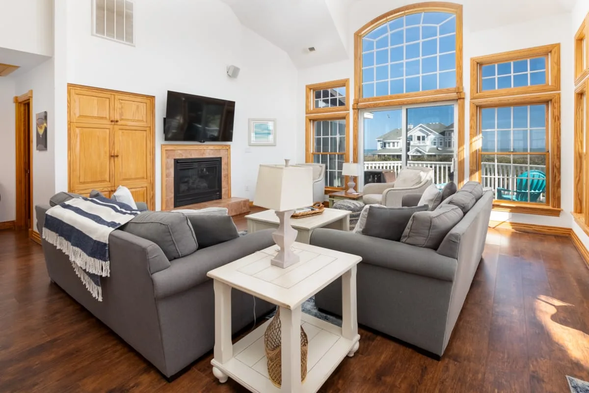 A bright living room with gray seating and large windows.