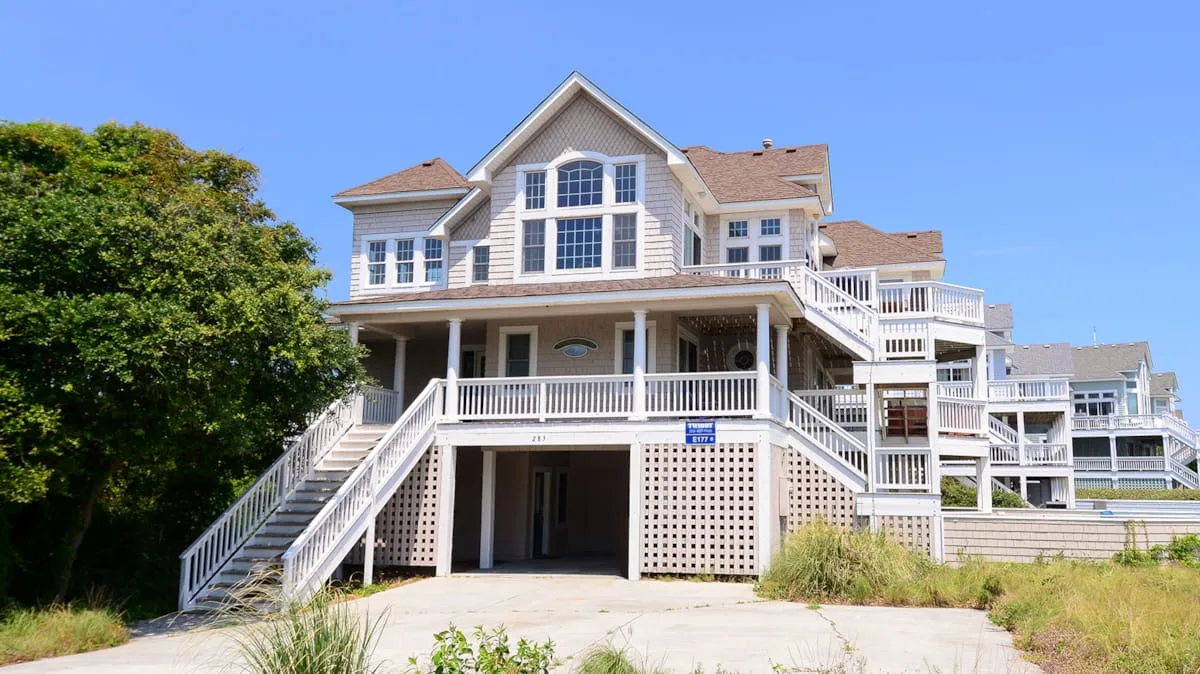 A large house with white balconies and exterior staircases under a clear blue sky.