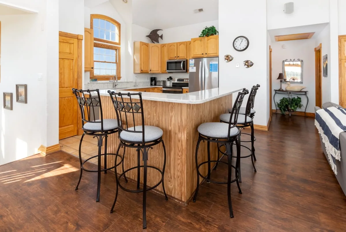 A kitchen and dining area with a wood-fronted counter and bar seating.