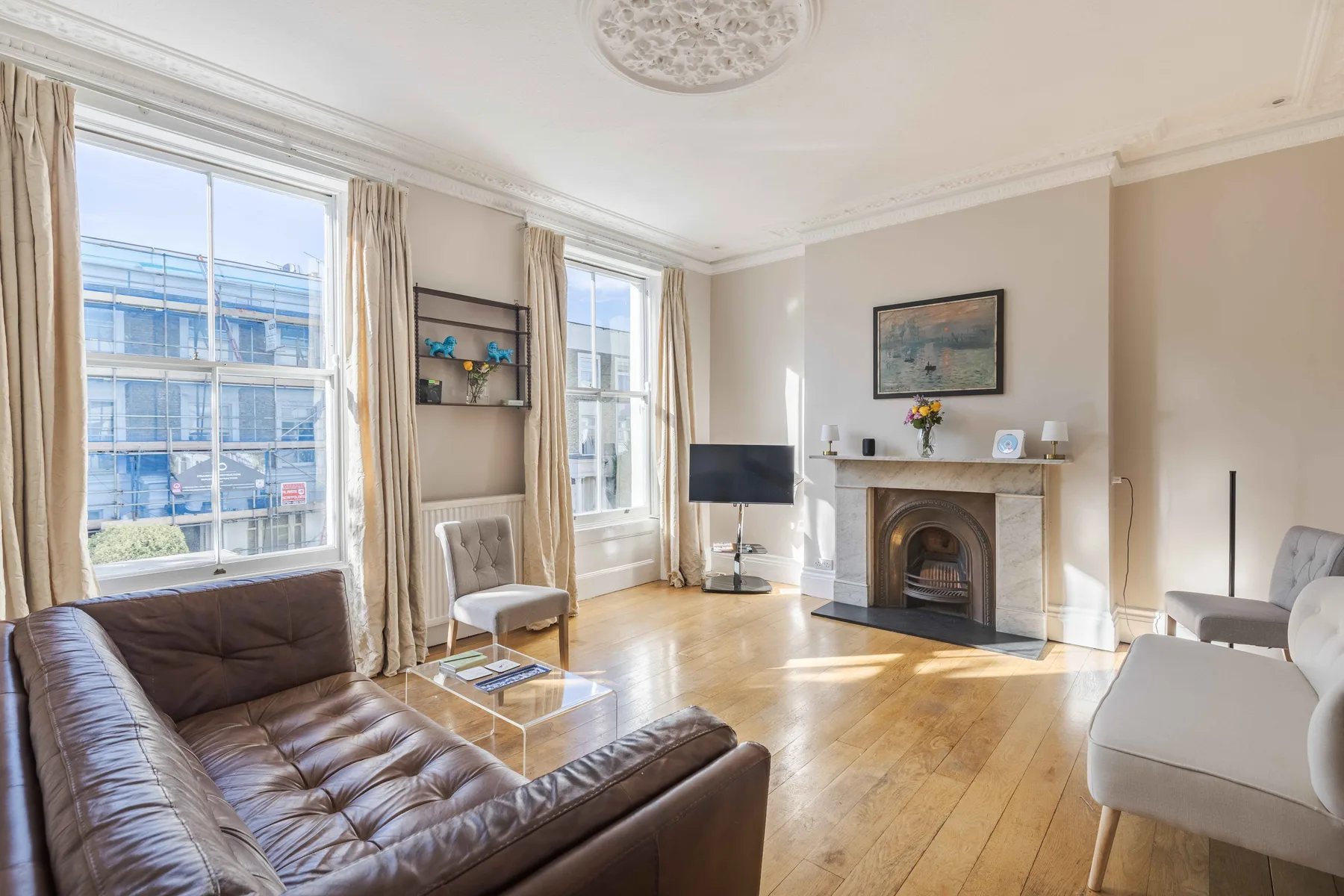 A bright living room with large windows, seating, and a fireplace.